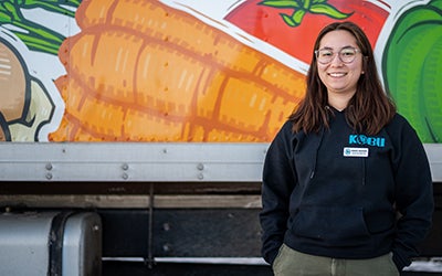 Grace poses in front of a food delivery truck in a Kobu sweatshirt.