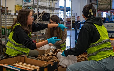 Grace in a yellow safety vest directing other students who are sorting donations.