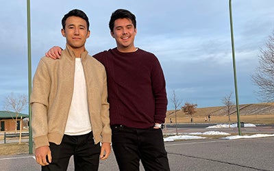 Two students pose on a basketball court.