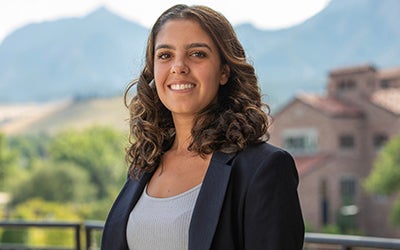 Anya Aidun in professional attire. The Flatirons and CU Boulder campus are visible in the background.