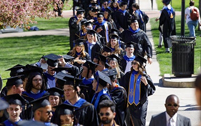 Graduates process into the Macky Center for commencement.