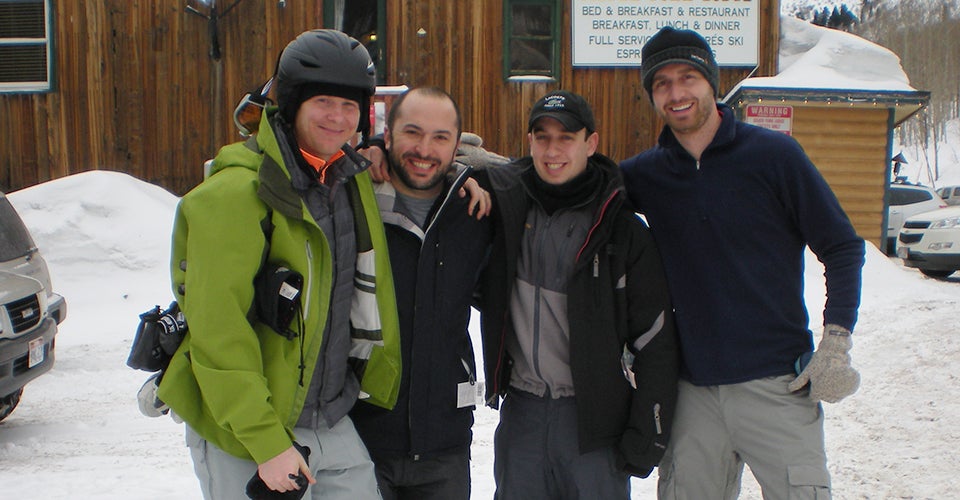 Four men in winter gear stand in front of a ski hotel in Utah.