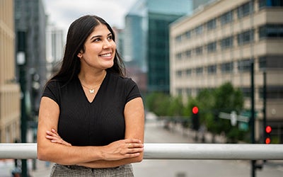 Isha Batra looks off into the distance. The Denver skyline is behind her.