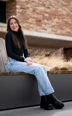 Kyla Thomas sitting in front of the Koelbel Building.