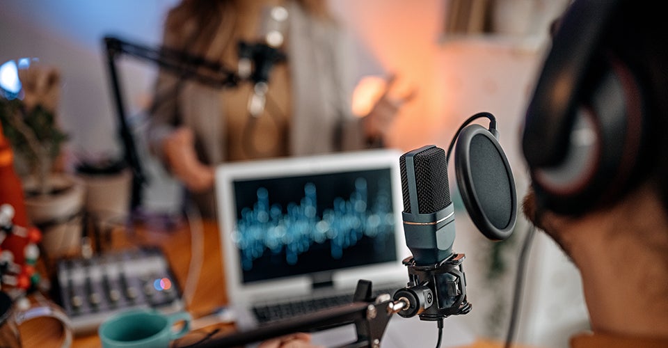 A host and guest prepare for a podcast interview in a studio.