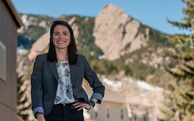 Megan in professional attire at Chautauqua Park. The Flatirons are visible in the background.