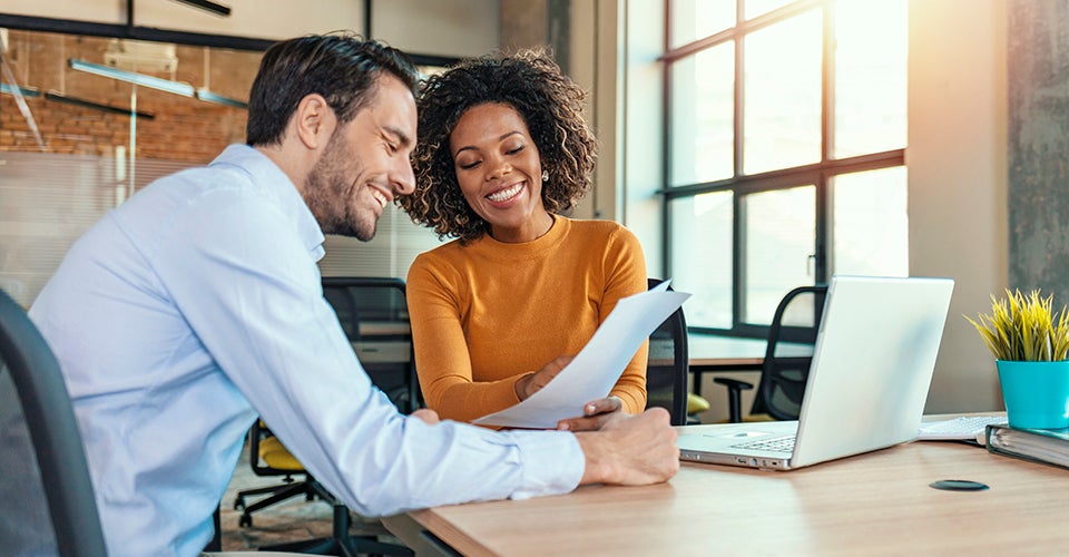 A man and young woman work together on a project in a modern office space.