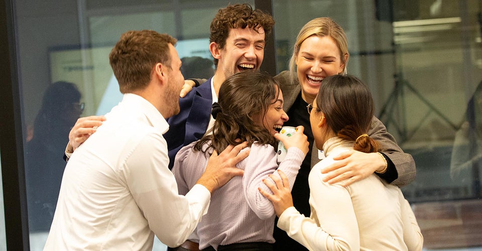 A group of students embrace and celebrate after winning a competition.