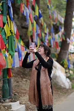 Nikki Bechtold holds up her phone to take a photo of the colorful flags surrounding her