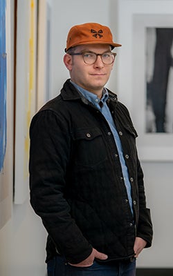 Tim Weiss in Optera's office. He wears a baseball cap with the company's logo on it.