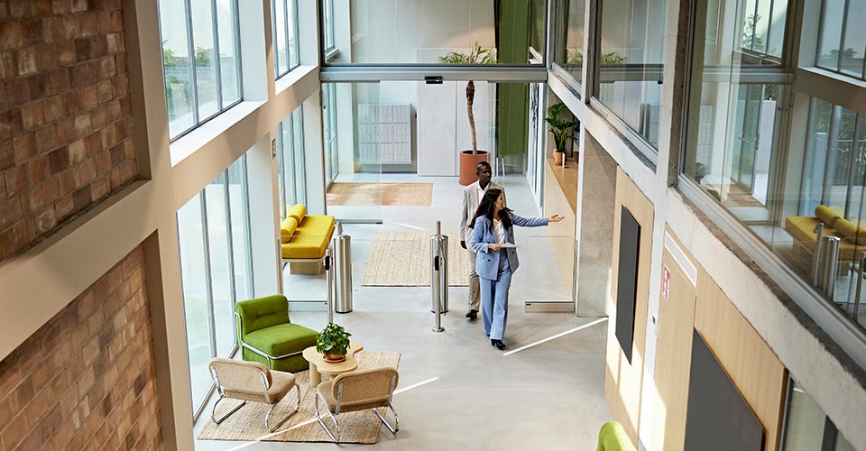 A woman shows a modern office space to a professional. 