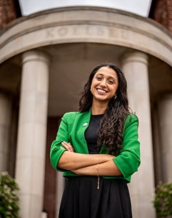 Trisha Tyagi smiles at the camera while posing in front of the Koelbel Building..