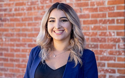 Headshot of Natalie against a brick wall.