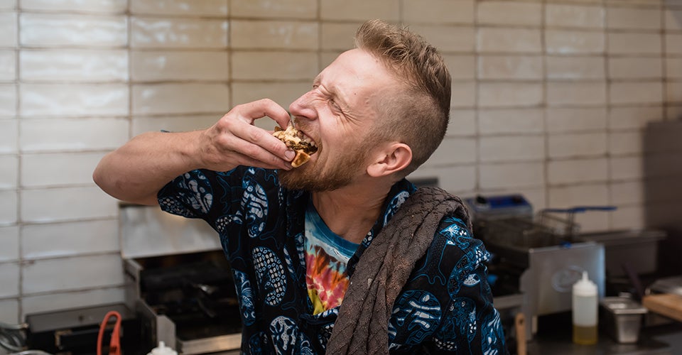 James Fogerty biting into one of his waffle creations at his kitchen. He's really enjoying it.