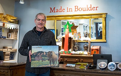 Chris Wirth folds a framed Forever Buffs puzzle in his Boulder showroom.
