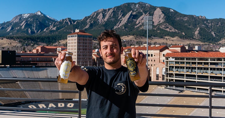 Alex Birkner holds his yerba mate in front of Folsom Field.