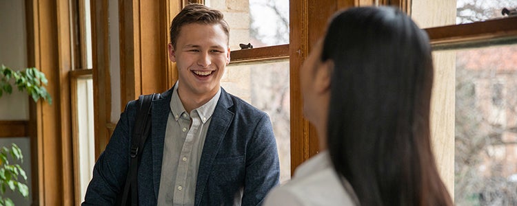 A student and peer mentor share a laugh in a hallway.