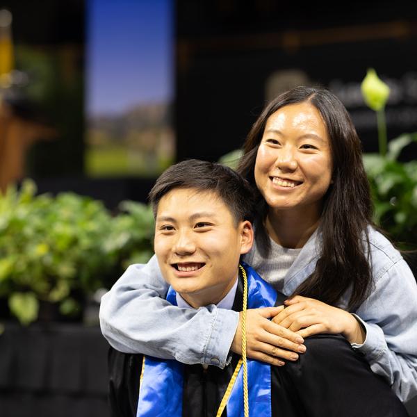 A graduate and family member pose for a photo.
