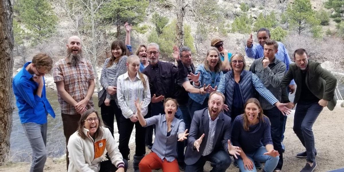 Rural Colorado Workshop participants standing in front a stream in the woods