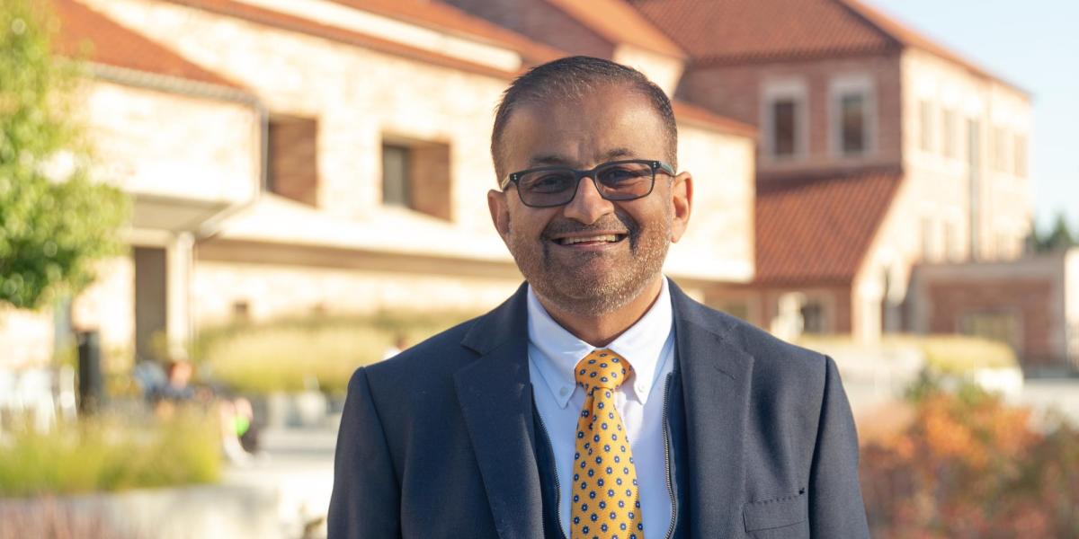 Dean Khatri smiles while posing outside of the Koelbel Building