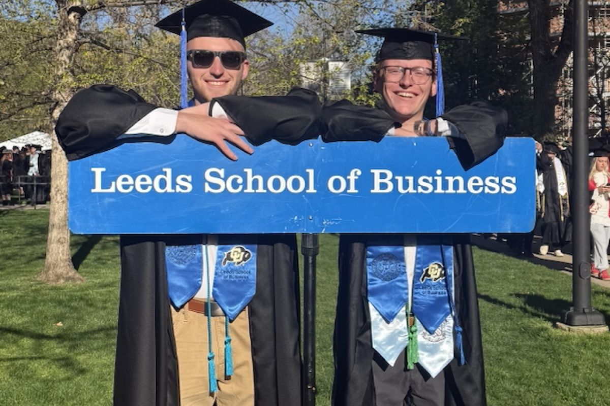 Graduates pose with the Leeds School of Business procession sign at CU Boulder Commencement