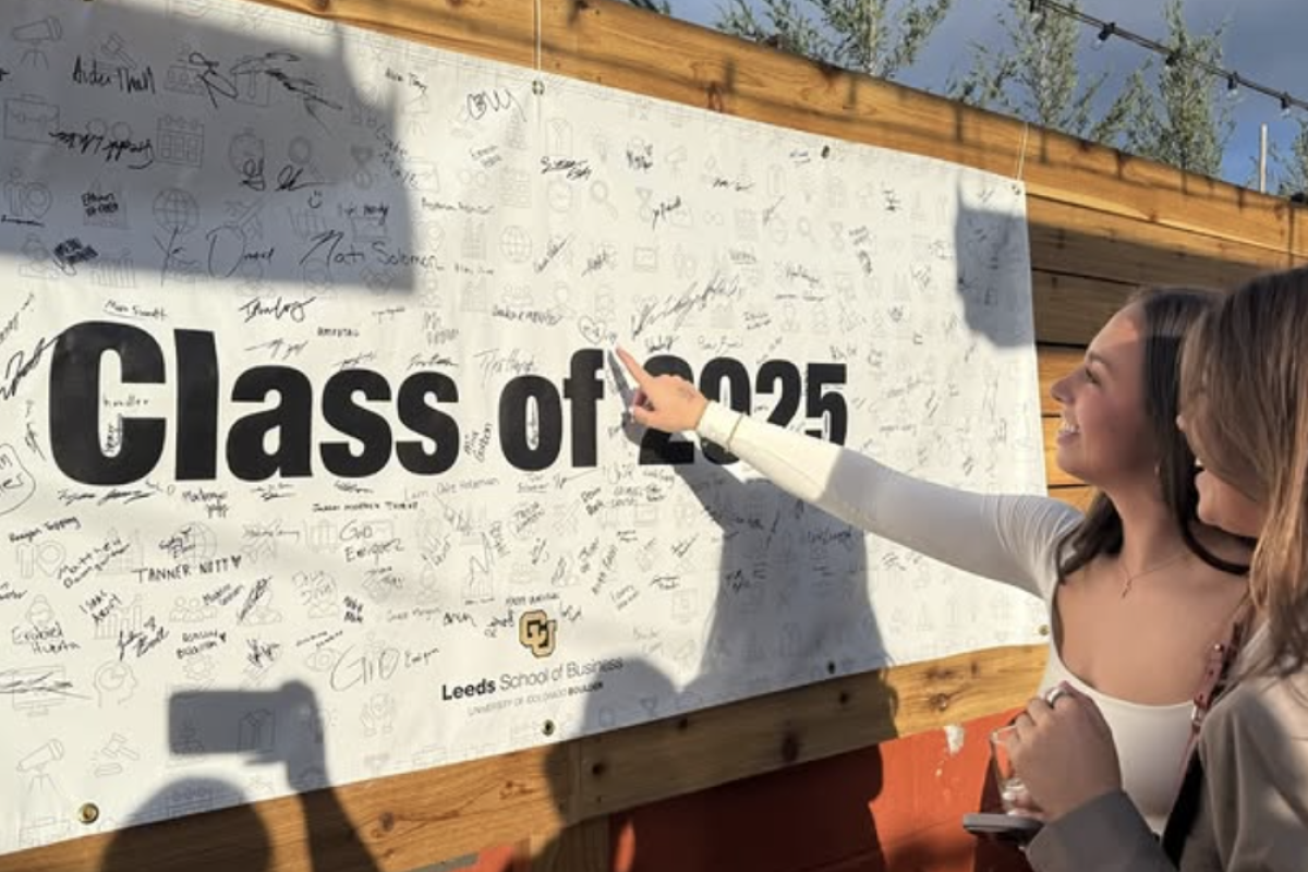 Students point to their signatures on the Class of 2025 banner