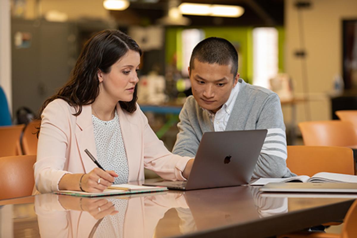 Two people have a conversation over a laptop.