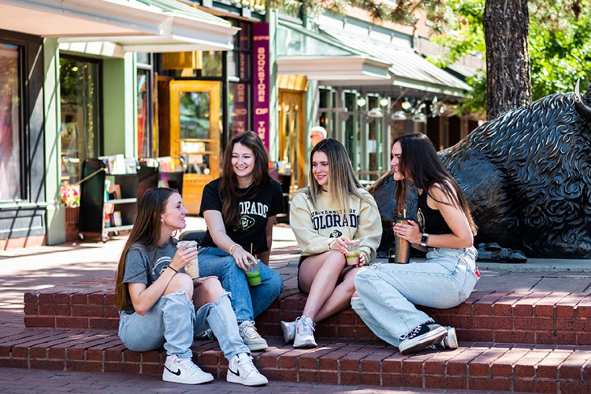 A group of female students at the Pearl Street Mall in Boulder, with a buffalo statue in the background.