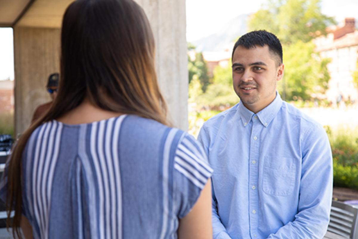 Student speaks with a mentor outside of the Rustandy Building.