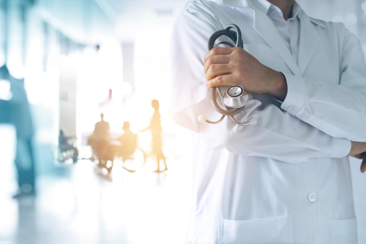Closeup of a doctor. Other medical professionals can be seen in the background.