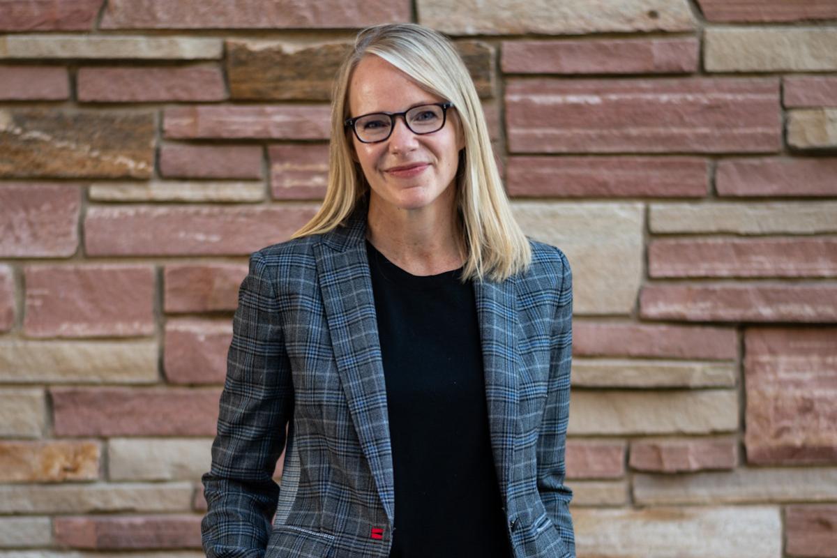 Kristin poses in professional dress against a brick wall.