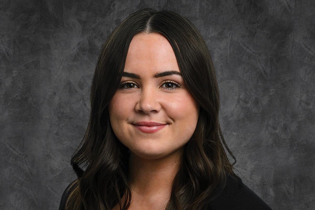 Professional portrait of Maeve against a dark background.