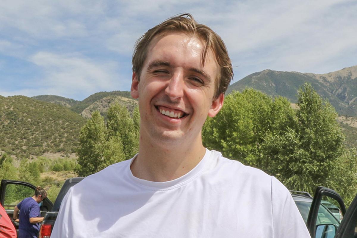 Connor stands outside with the Flatirons in the background.