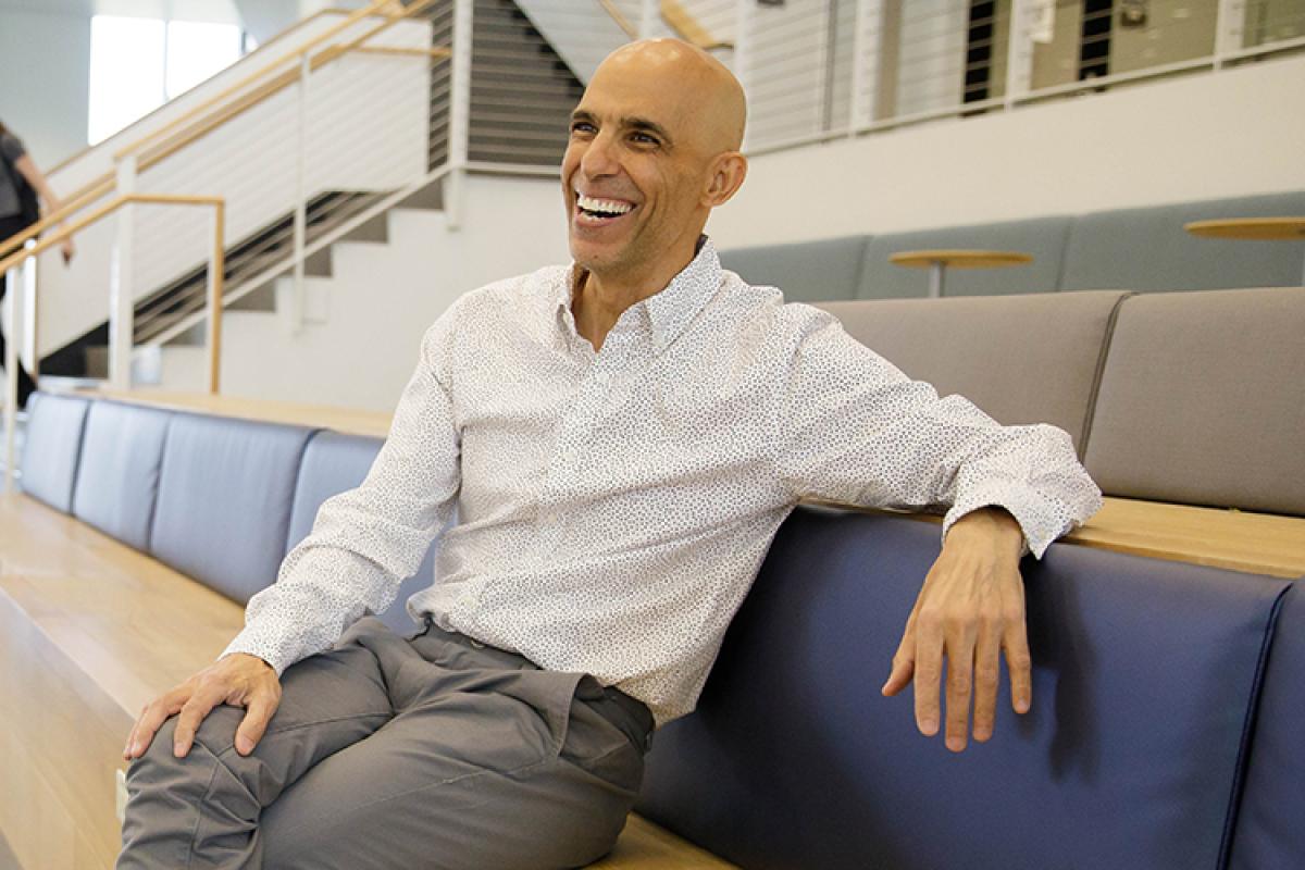 Rico laughs while sitting in a casual work area in the Rustandy Building.