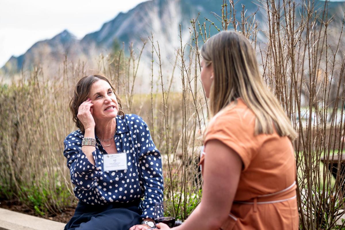 older woman mentoring younger woman, flatirons in background