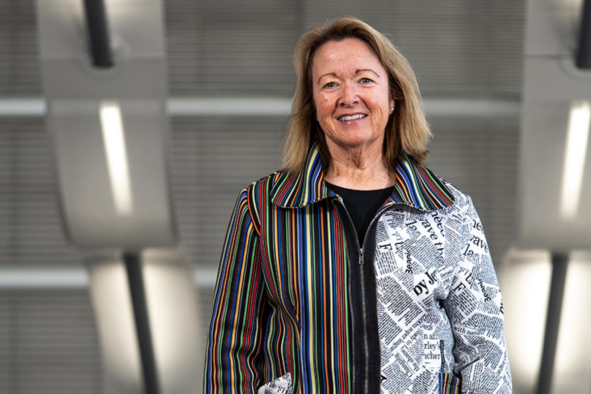 Libby Adams in a bright jacket, standing in a stairwell.