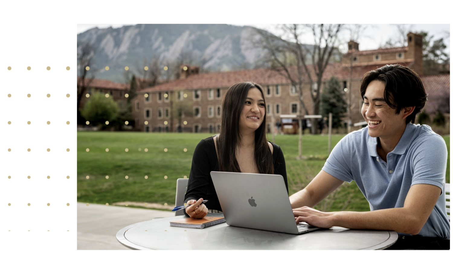 Two students look at a computer while laughing