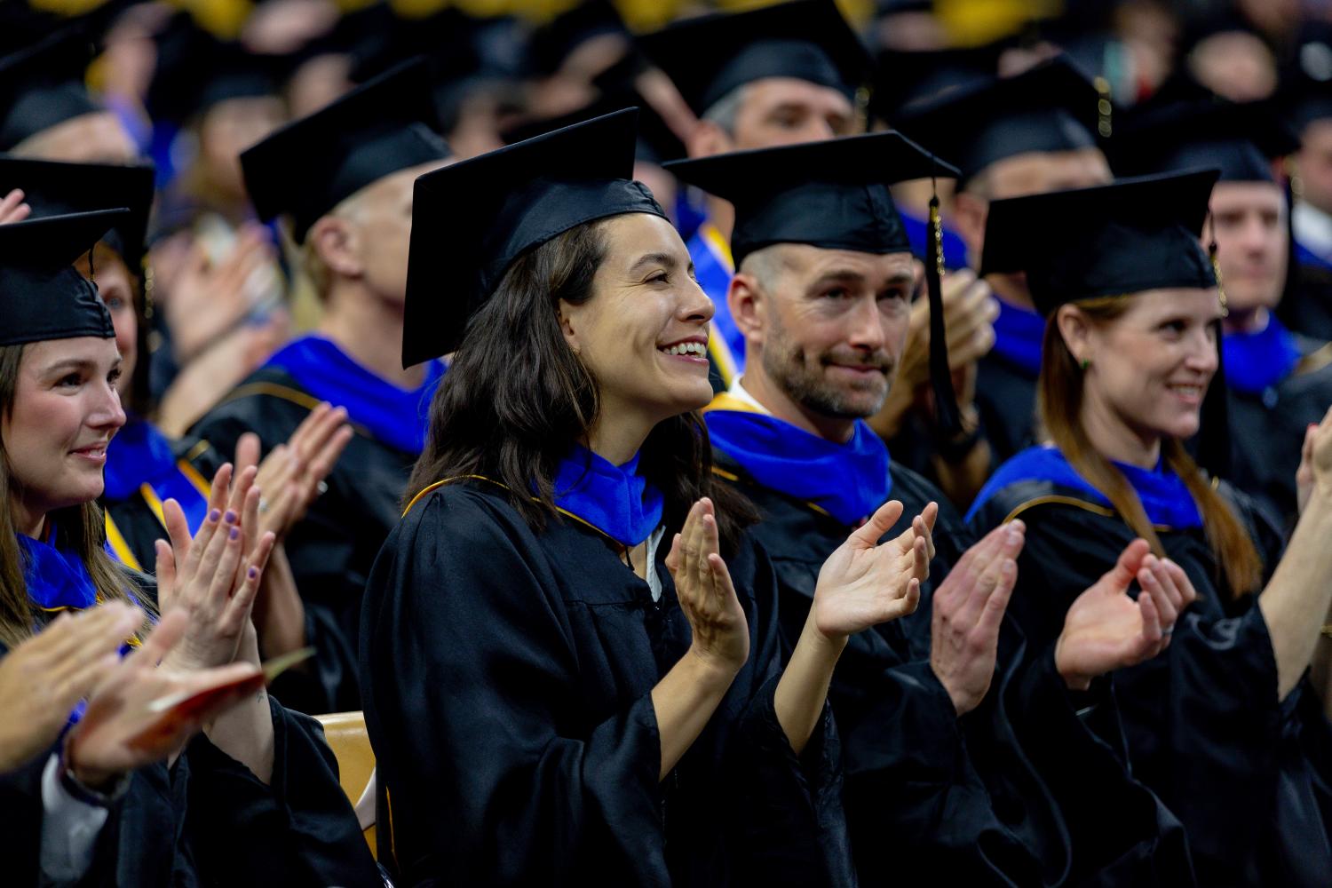 Graduating grad students clap in the audience of their recognition ceremony