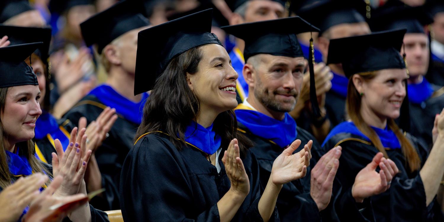 Graduating grad students clap in the audience of their recognition ceremony