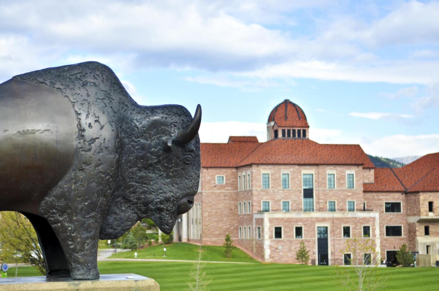A buffalo statue appears in the foreground with the Koelbel Building in the background.