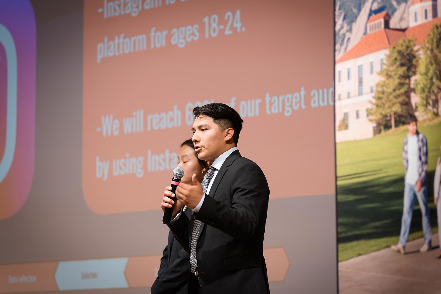 A student in the Business Leadership program speaks into a microphone while delivering a presentation as part of the program.