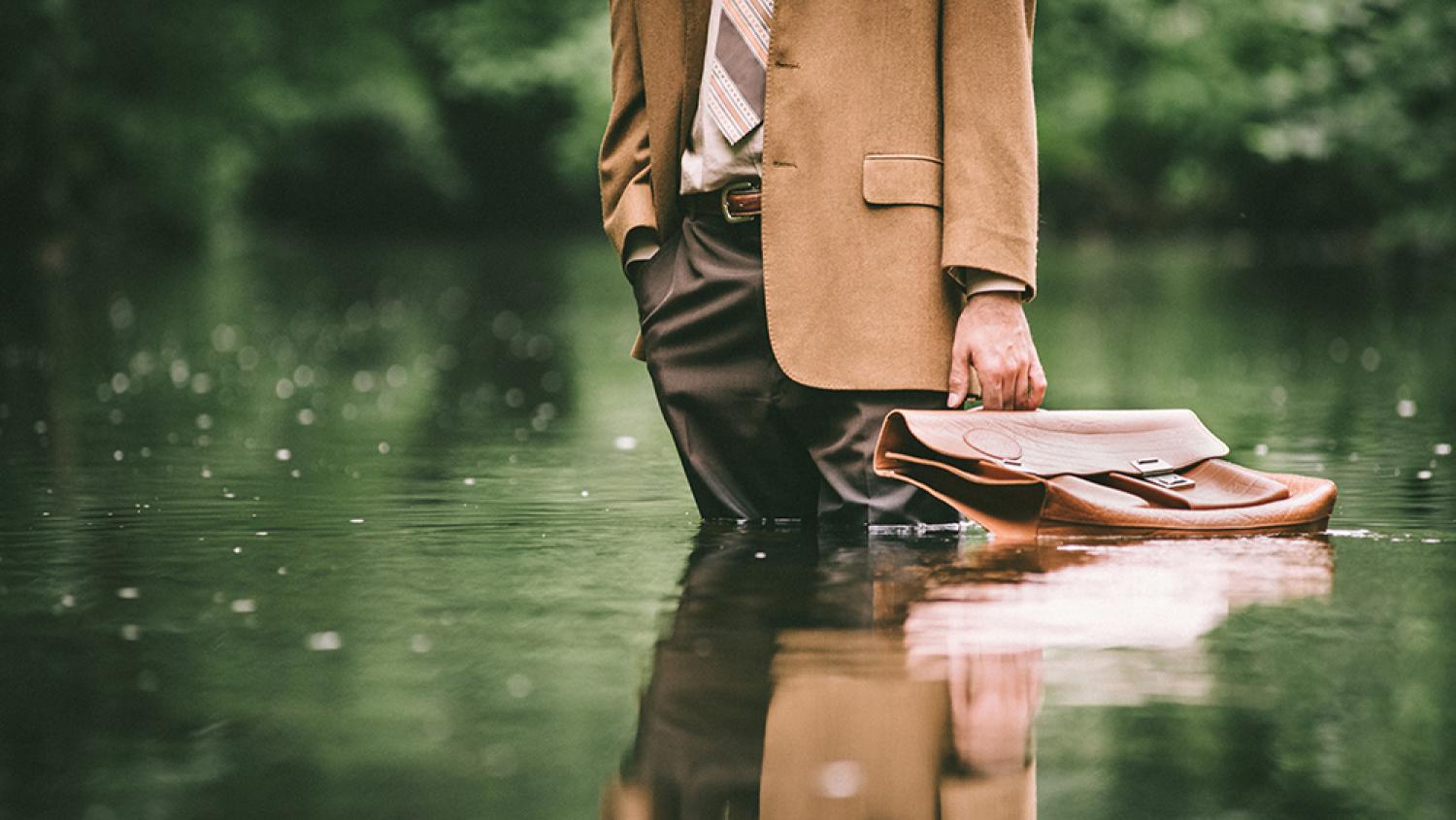 A businessman stands up to his calves in water.