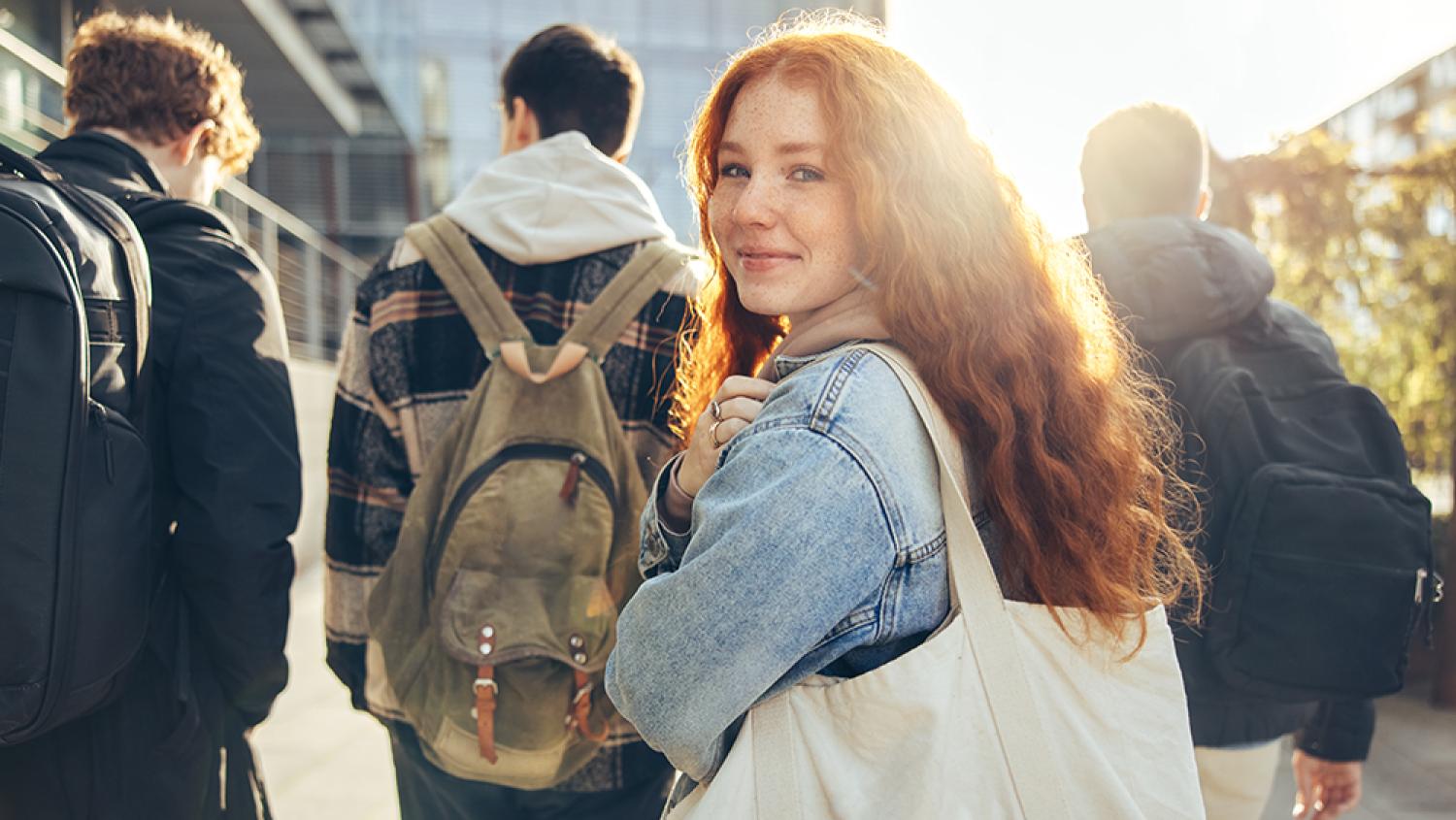 A woman in a group of students looks over her shoulder at the camera.