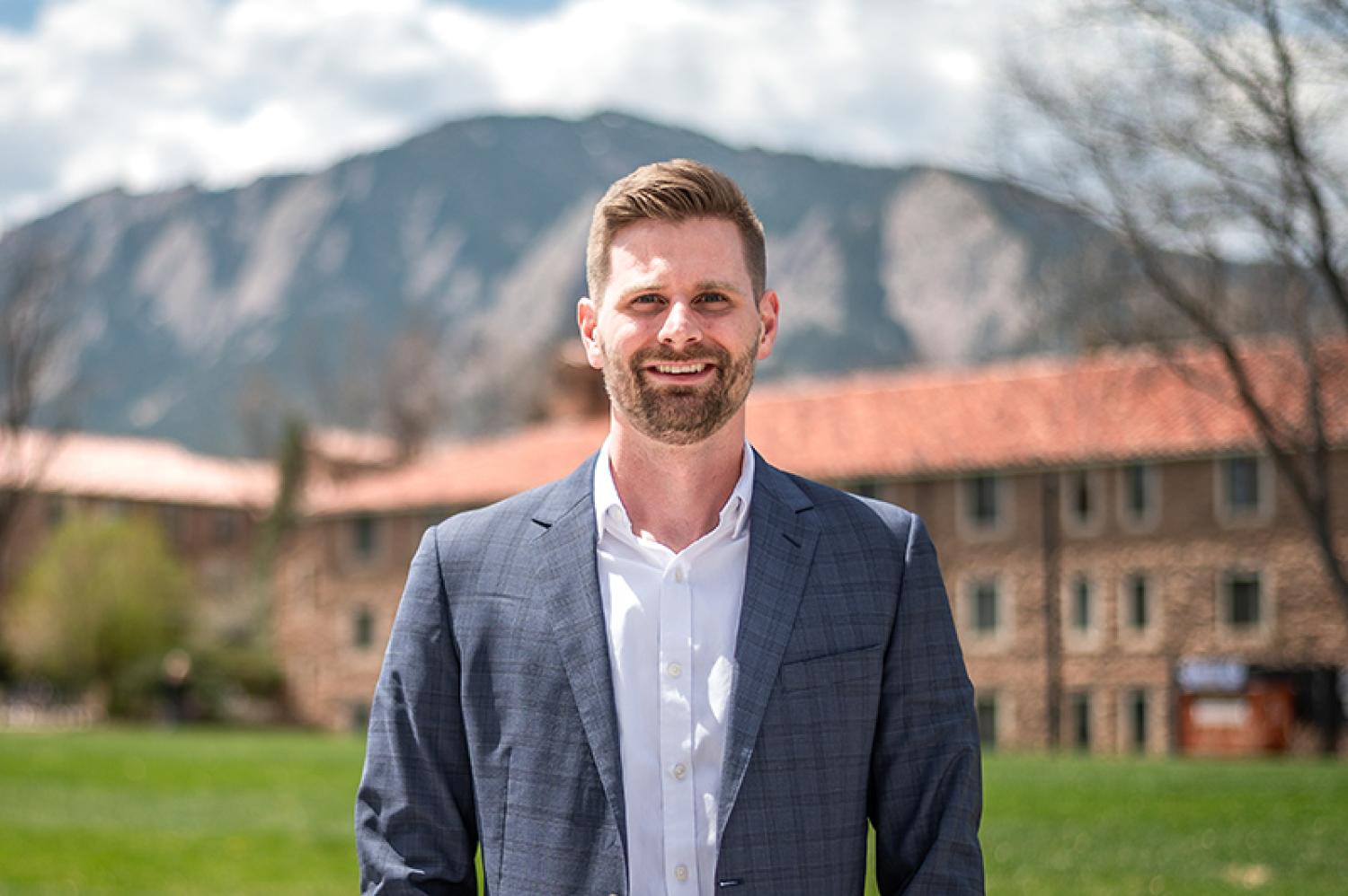 Ezra McPhail poses on campus with the Flatirons in the background