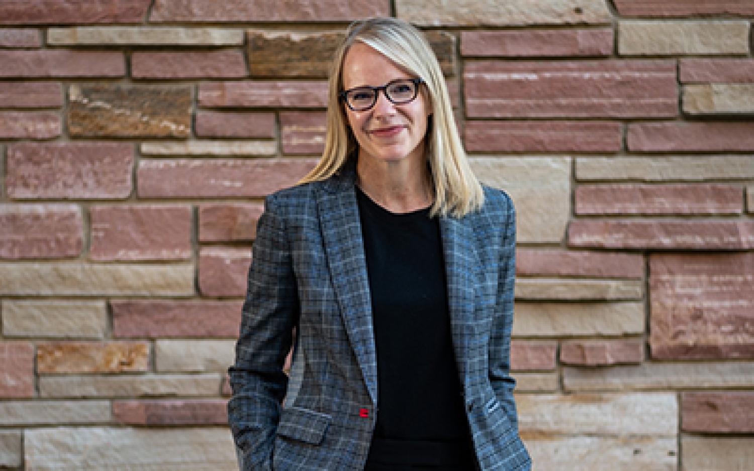 Kristin Apple in professional attire against a brick wall.
