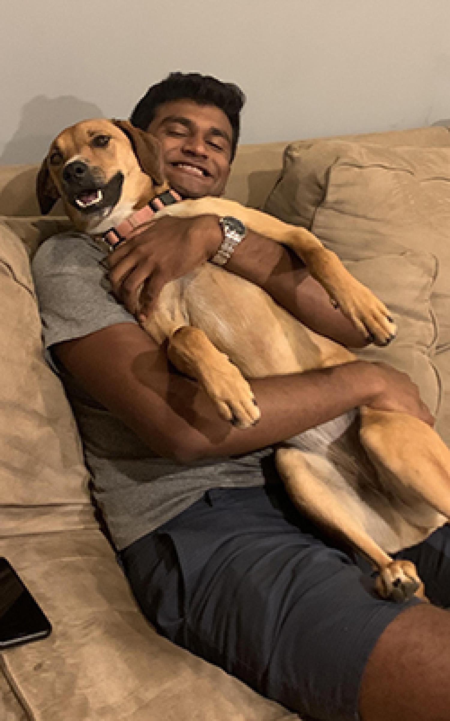 Atul Raguveer reclines on a brown couch with his dog.