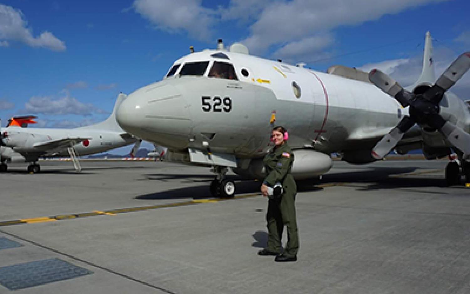 Taylor Hartley in front of a fleet of military jets on a runway.