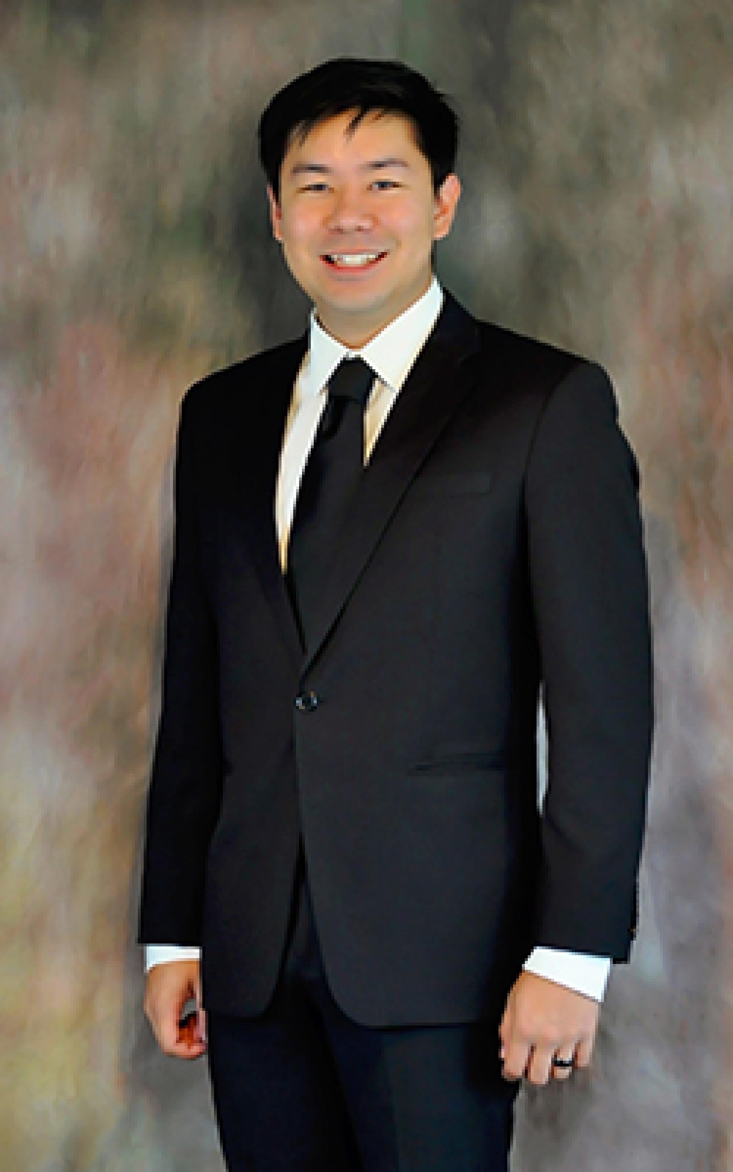 Michael Lau in a dark suit against a studio backdrop.