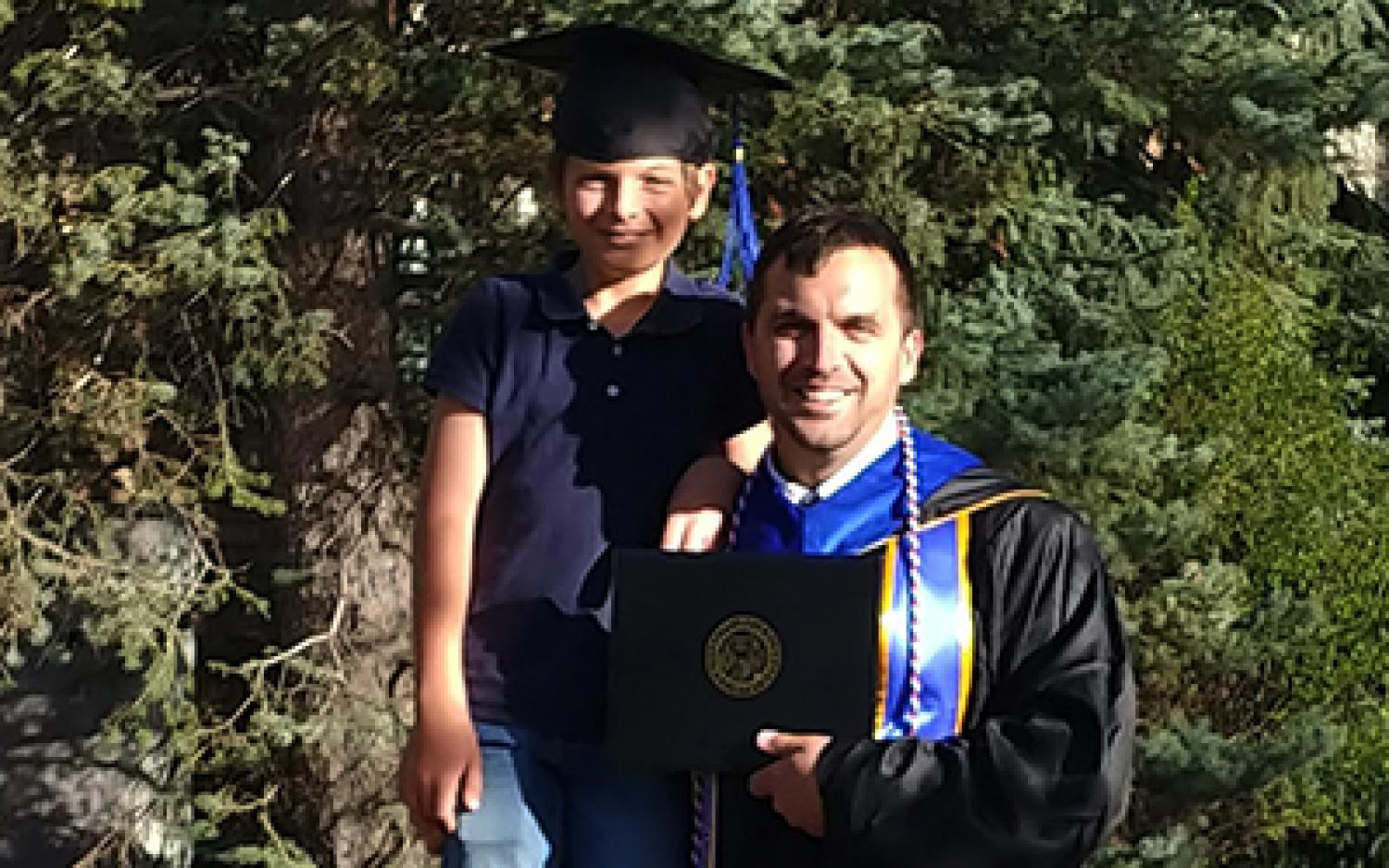 Harrison GreenMaki at graduation. A small boy is wearing his mortarboard.