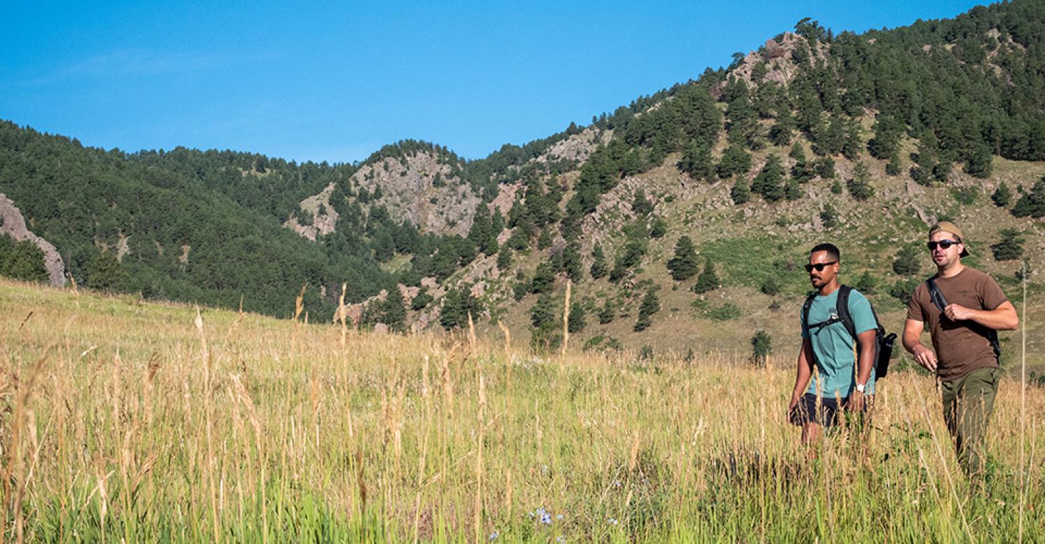 Two veterans hiking in Chautauqua park. The foothills of the Rocky Mountains can be seen in the back.